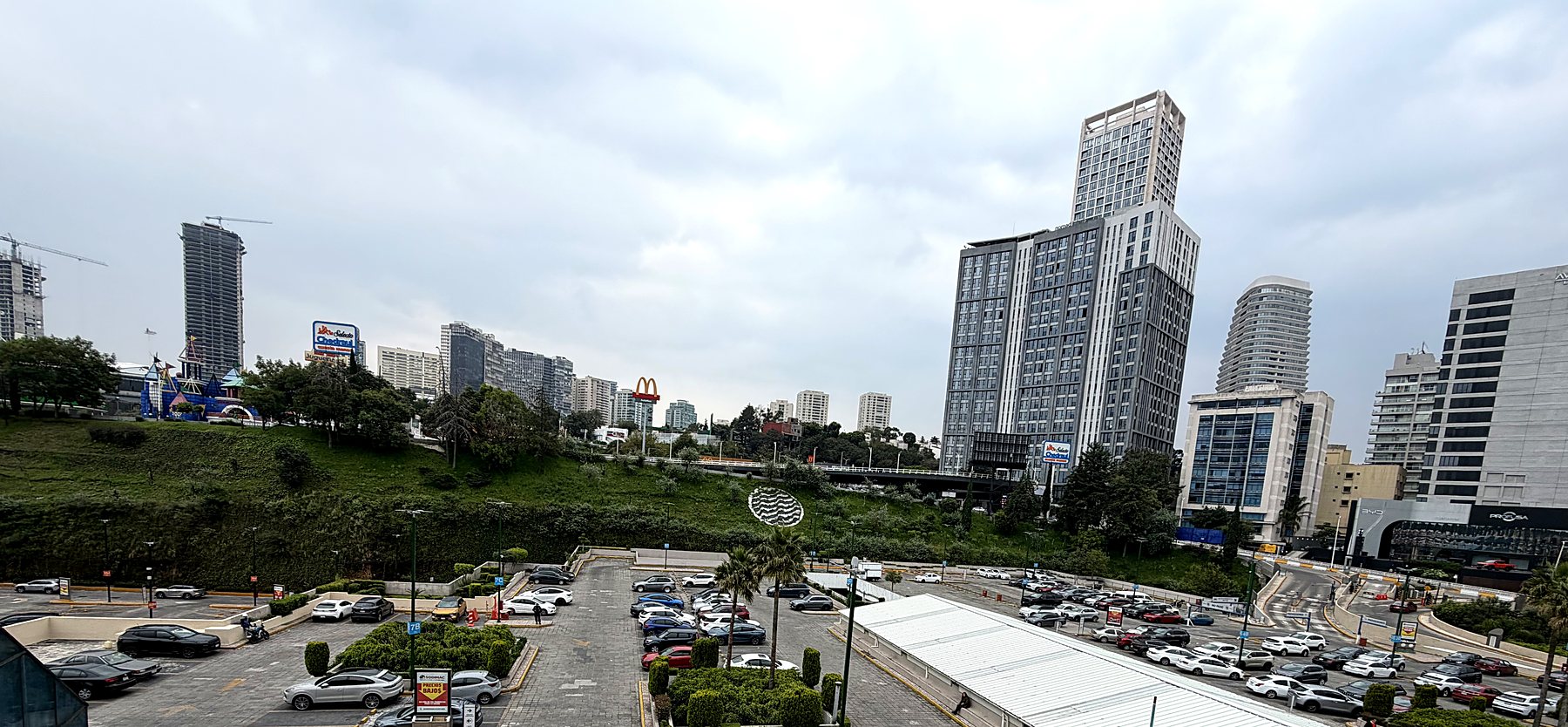 Panorámica del estacionamiento, áreas ajardinadas y bahías techadas del centro comercial