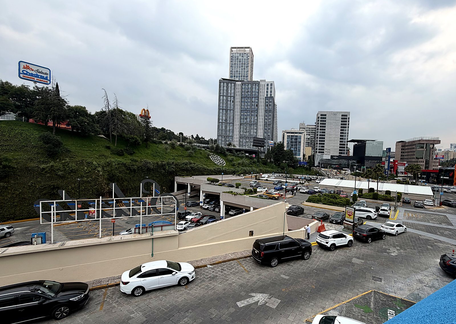 Vista elevada del estacionamiento de la plaza con el entorno urbano de Interlomas